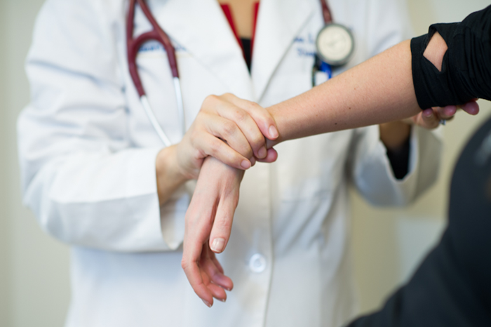 A rheumatologist examines a patient's hand and wrist. 