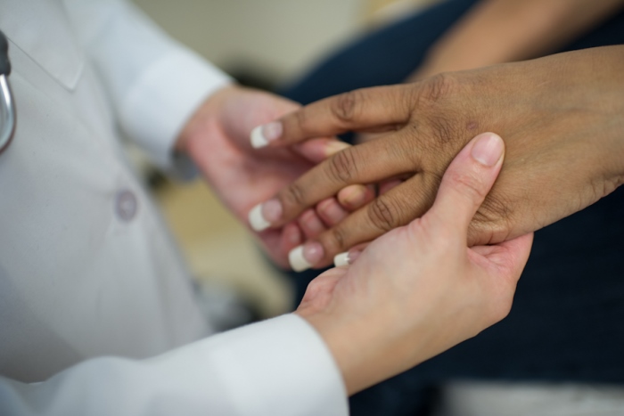 A rheumatologist examines the hands of a patient with rheumatoid arthritis.