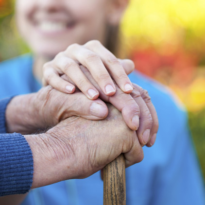 A young femaie holds the inflamed hands of a man with rheumatoid arthritis.