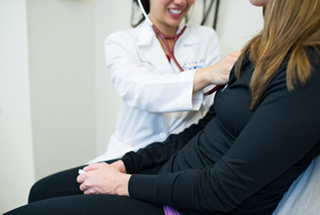 A smiling rheumatologist performing an exam on her patient